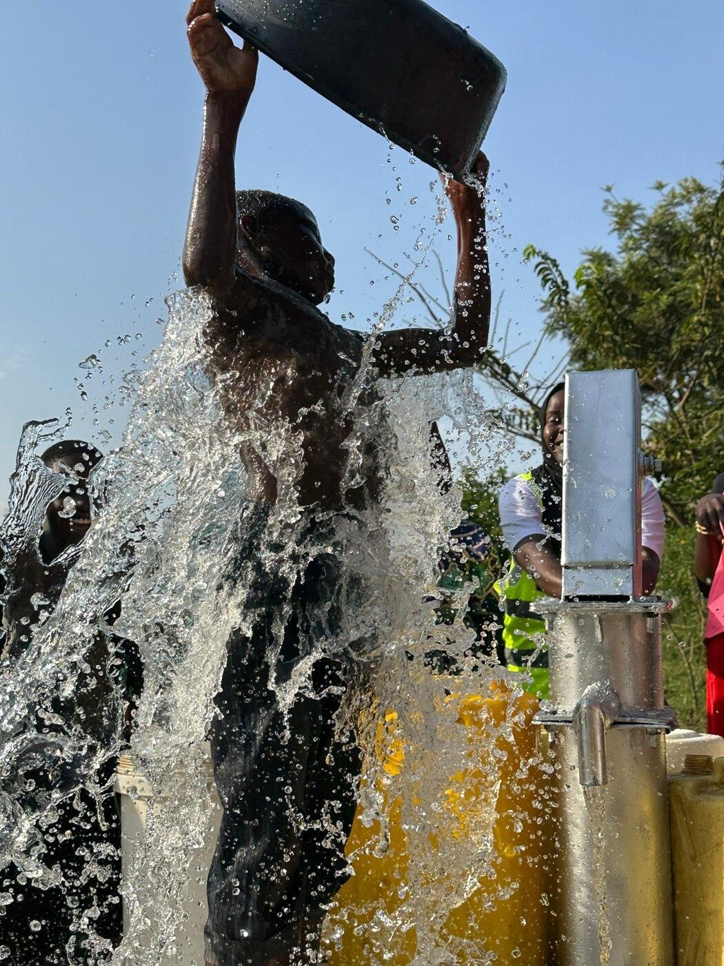 A child pours a fresh splash of clean water from a newly installed pump