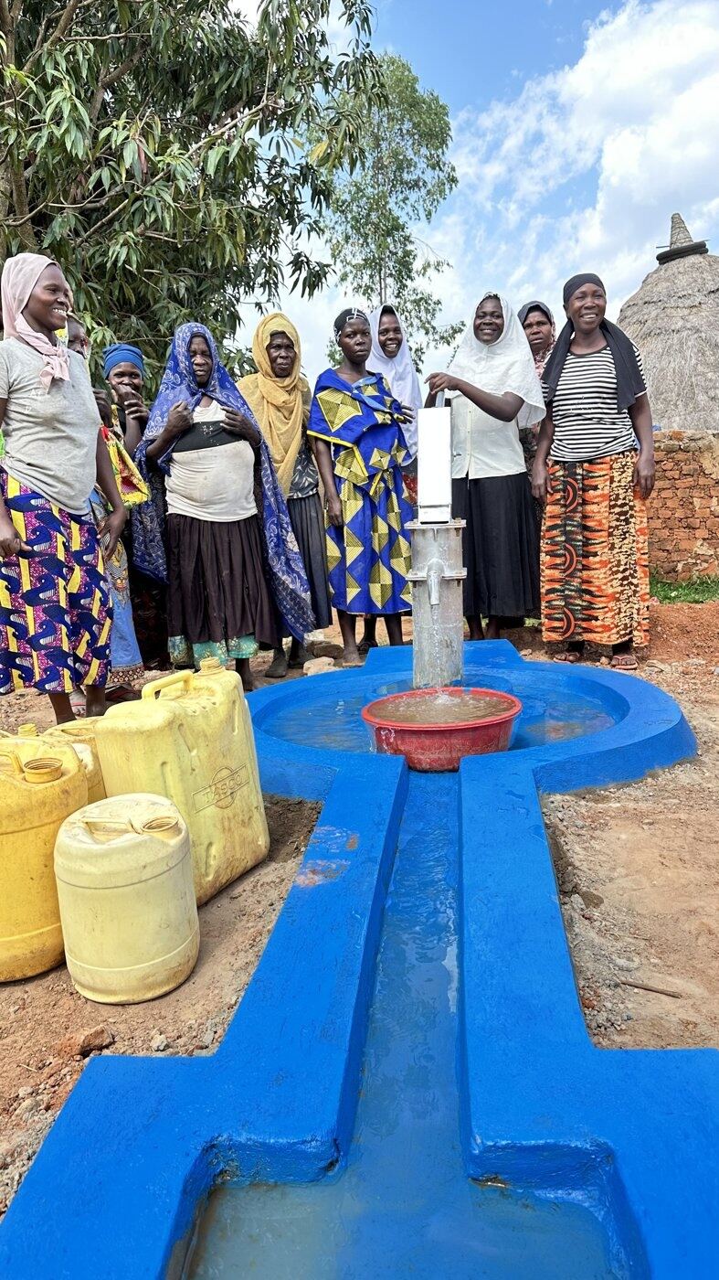 A group of women standing together at a completed community water point
